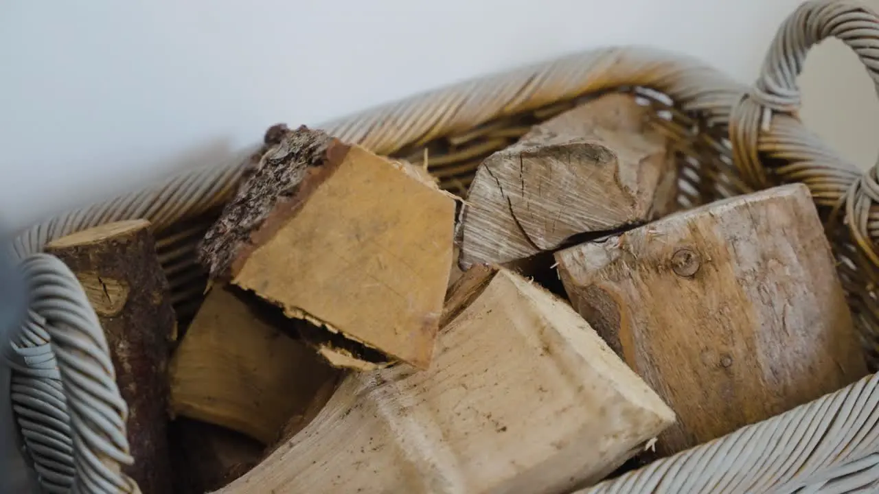 Log basket full of fresh cut wood next to fire in cosy english cottage