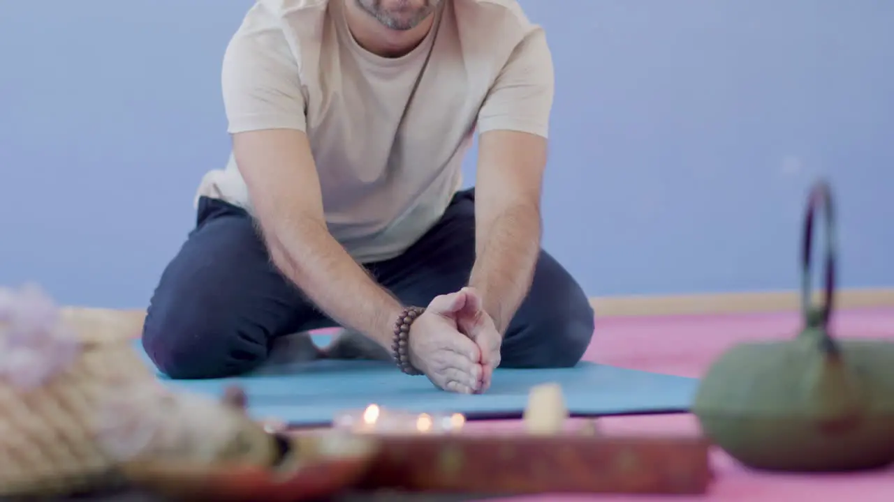 Man sitting on floor and practicing yoga with incense