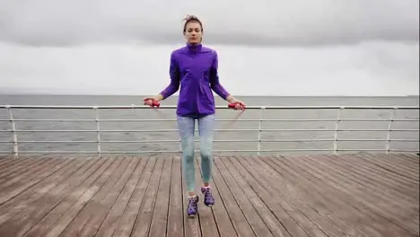 Young athletic woman working out on the jump rope Slim girl jumping on a skipping rope by the sea Slow Motion shot