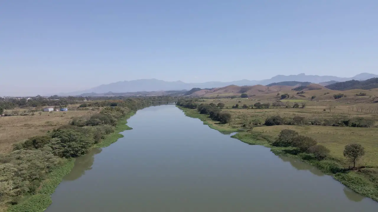 Paraíba do Sul river in Brazil riparian forest and deforestation with aerial view over the green water in the background mountains