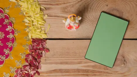 Hand Putting Statue Of Ganesh On Table With Green Screen Digital Tablet In Festival Of Diwali