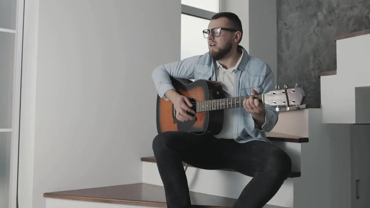 Male Musician Singing And Playing Guitar At Home