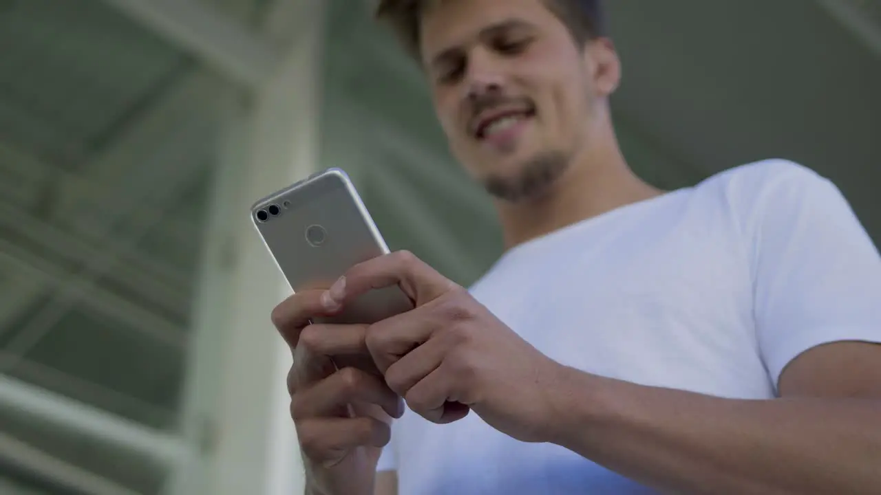 Smiling young man typing message on smartphone