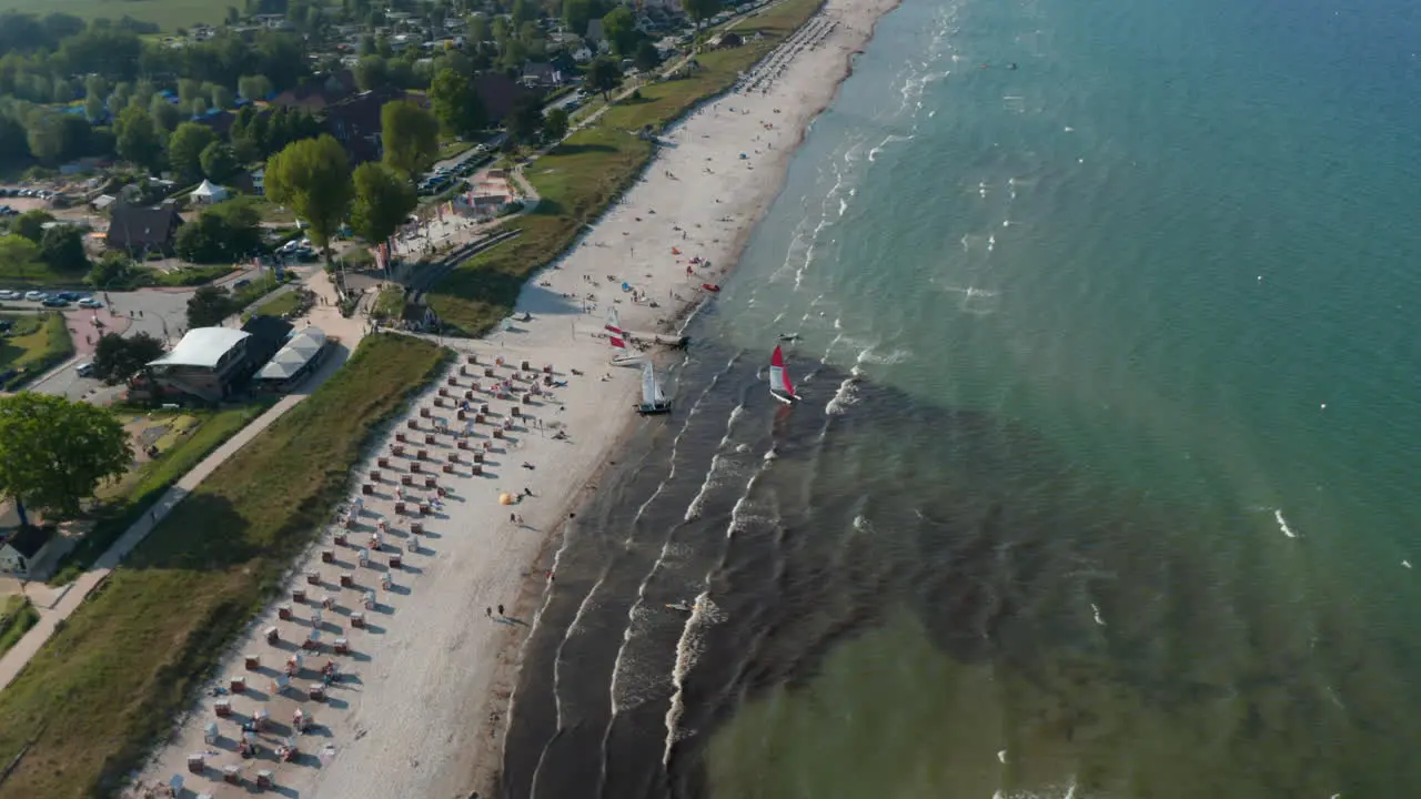 Aerial drone view of two sailboats in tourist beach at Baltic sea coastline Scharbeutz Germany circle pan day