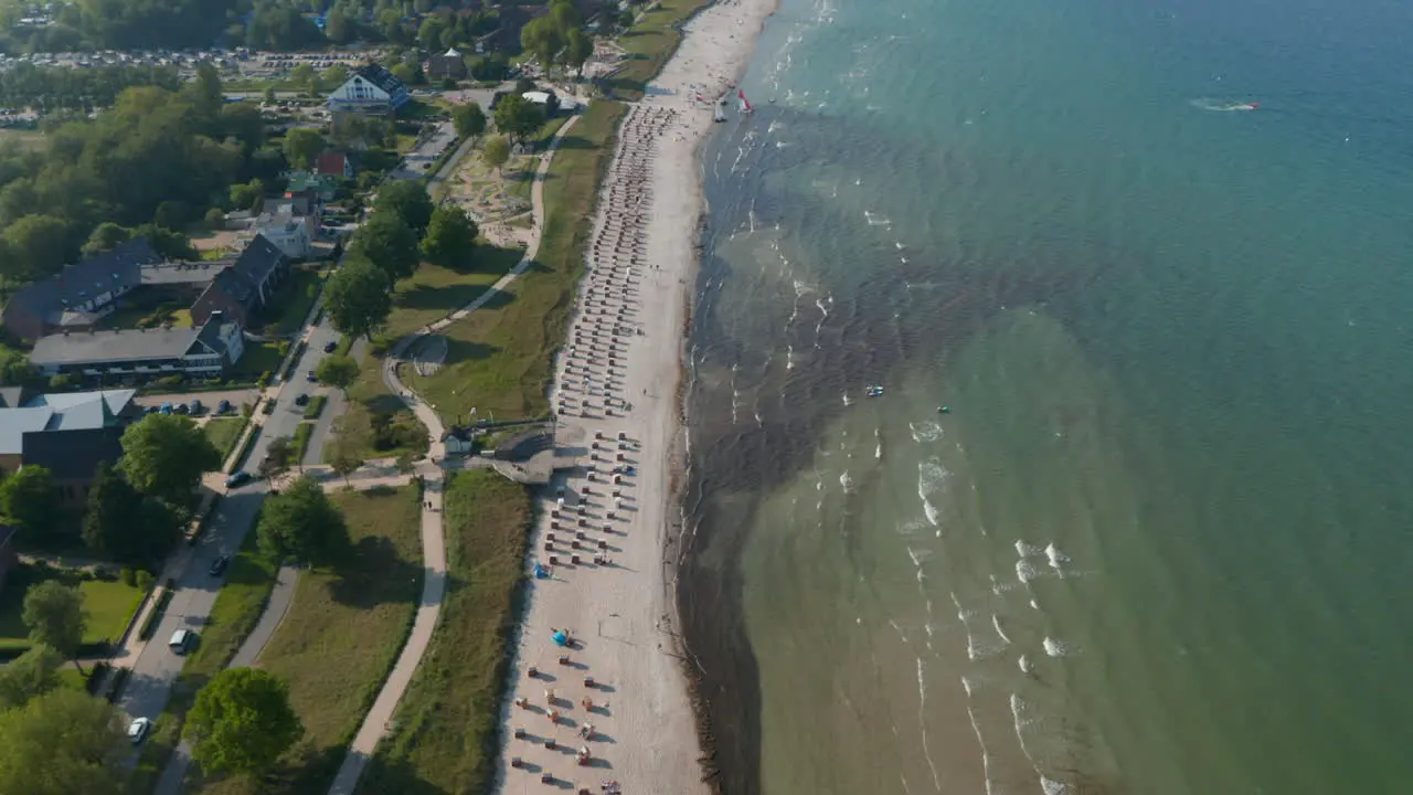 Majestic aerial drone view of travel destination tourist beach at Baltic sea in Scharbeutz Germany dolly in tilt down day