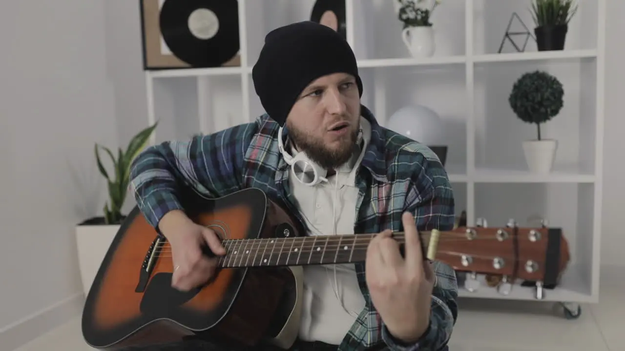 Male Urban Musician Singing And Playing Guitar At Home