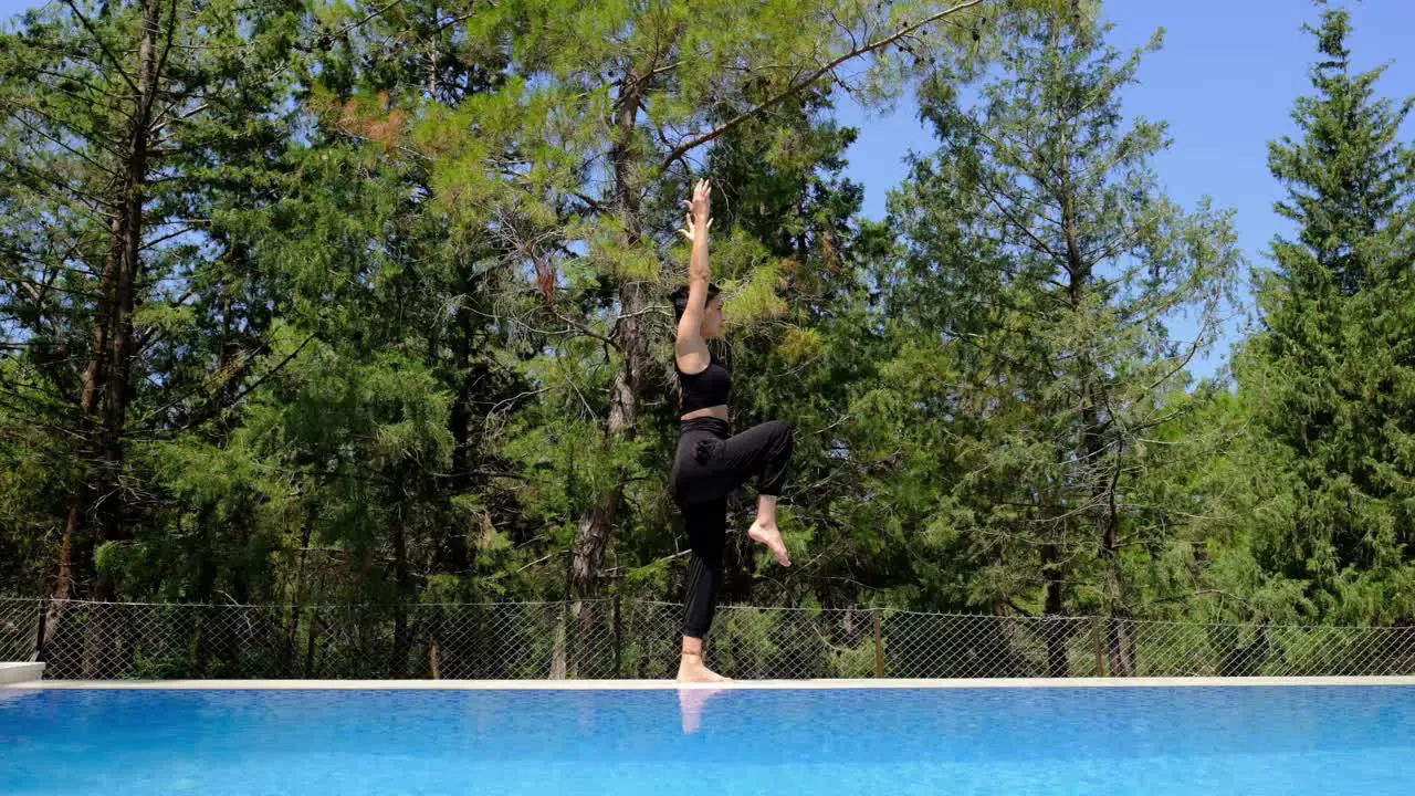 a woman does yoga by the poolside