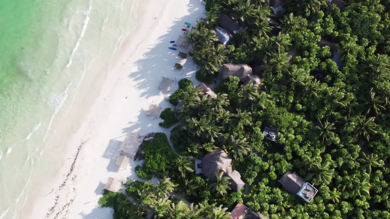 Top down aerial view of cabanas and huts on beautiful white sand beach in tropical paradise