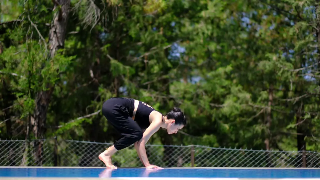 woman does yoga by the poolside