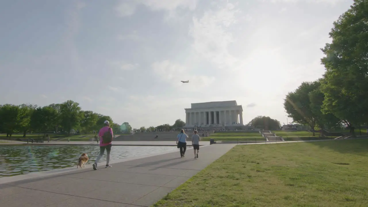 Pedestrians walk by the reflecting pool with the Lincoln Memorial in the background