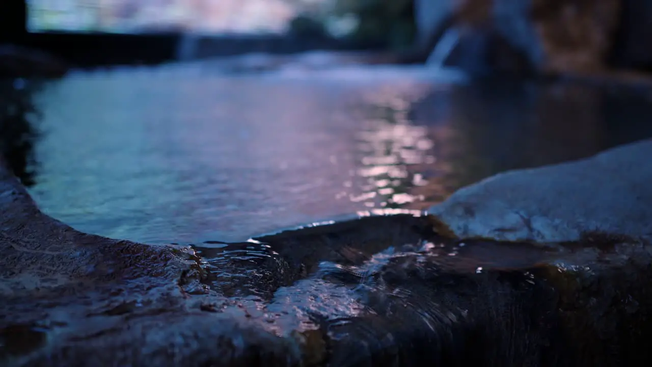 Japanese onsen water overflowing from stone bath at