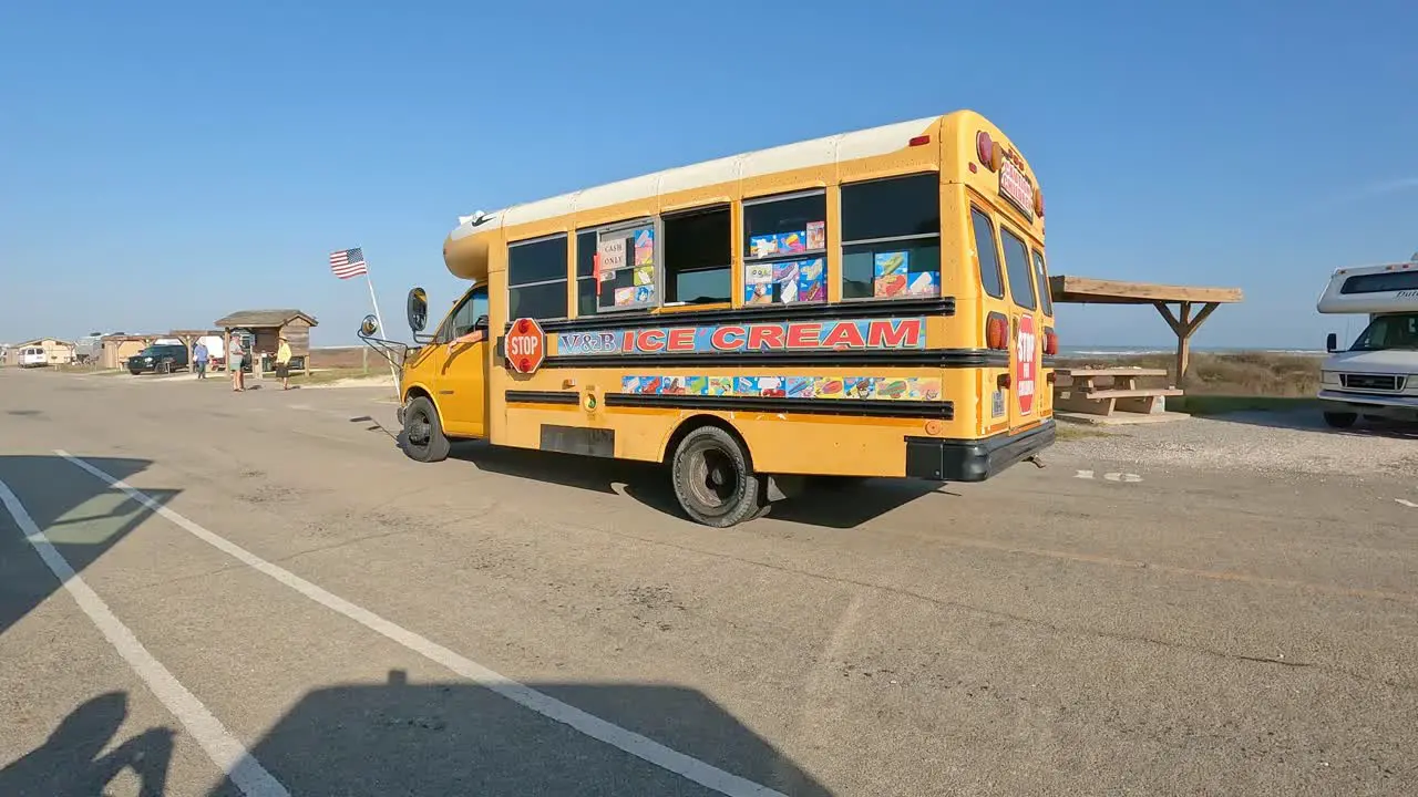 Converted school bus that is an ice cream vendor is driving thru a busy campground at Maliquite Campground at North Padre Island National Seashore