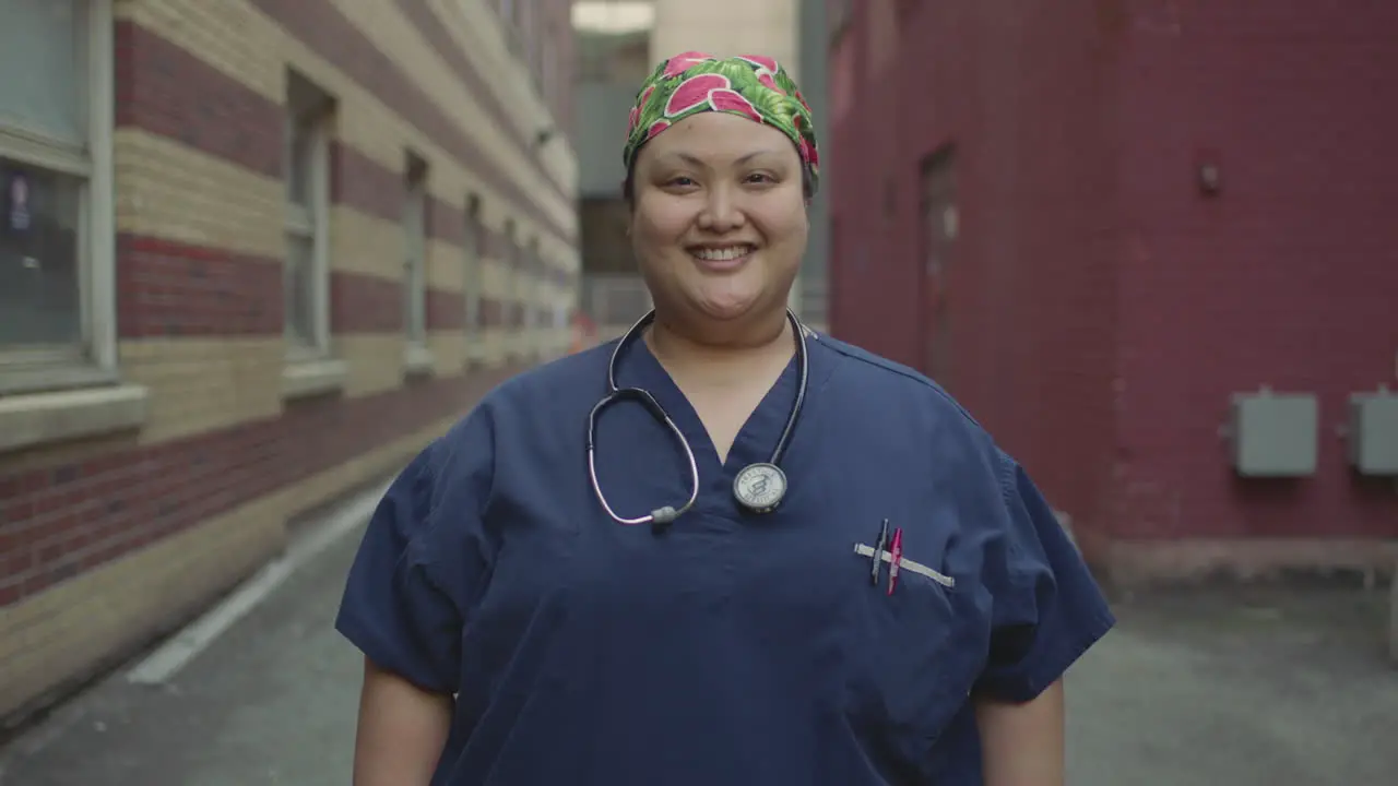 A nurse stands outside and takes her mask off