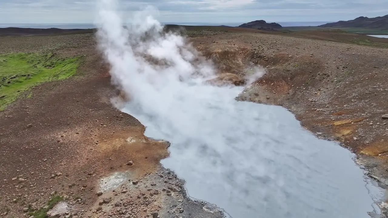 An aerial drone's forward view of Engjahver's steam lake on the Reykjanes Peninsula in Iceland hovering just above the steam