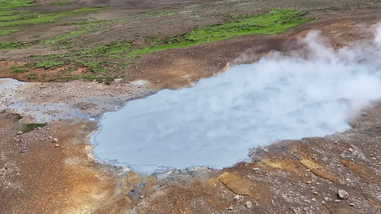 An aerial drone view with a quick movement then fixed on Engjahver's steam lake on the Reykjanes Peninsula in Iceland