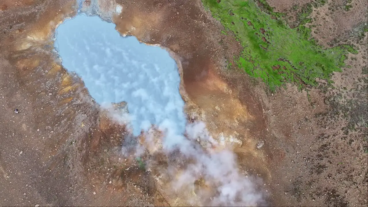 "An aerial drone's fixed view of Engjahver's steam lake on the Reykjanes Peninsula in Iceland with steam drifting to the right