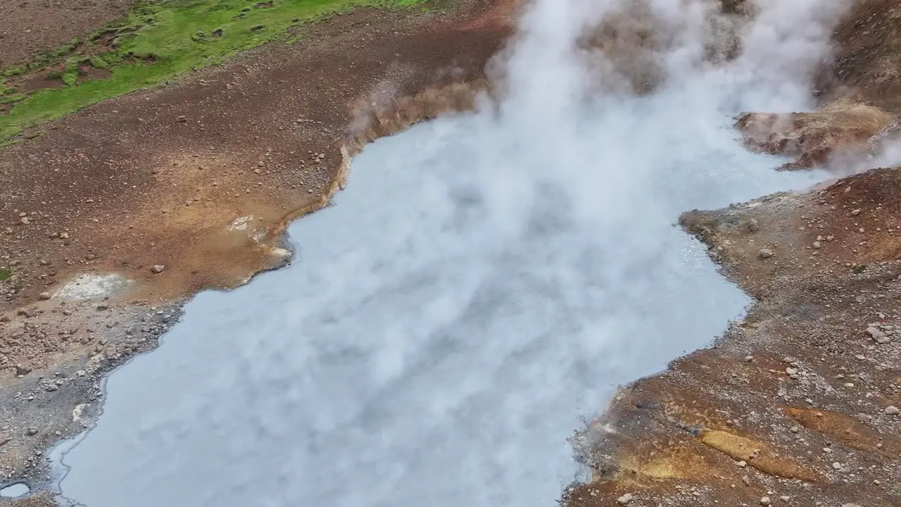 An aerial drone's orbit view from a medium altitude of Engjahver's steam lake on the Reykjanes Peninsula in Iceland