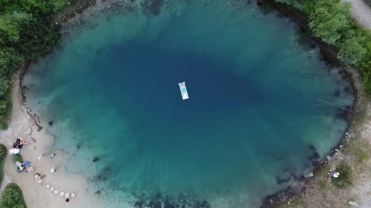 Adult person lying on floating water mat at Izvor Cetina spring Aerial