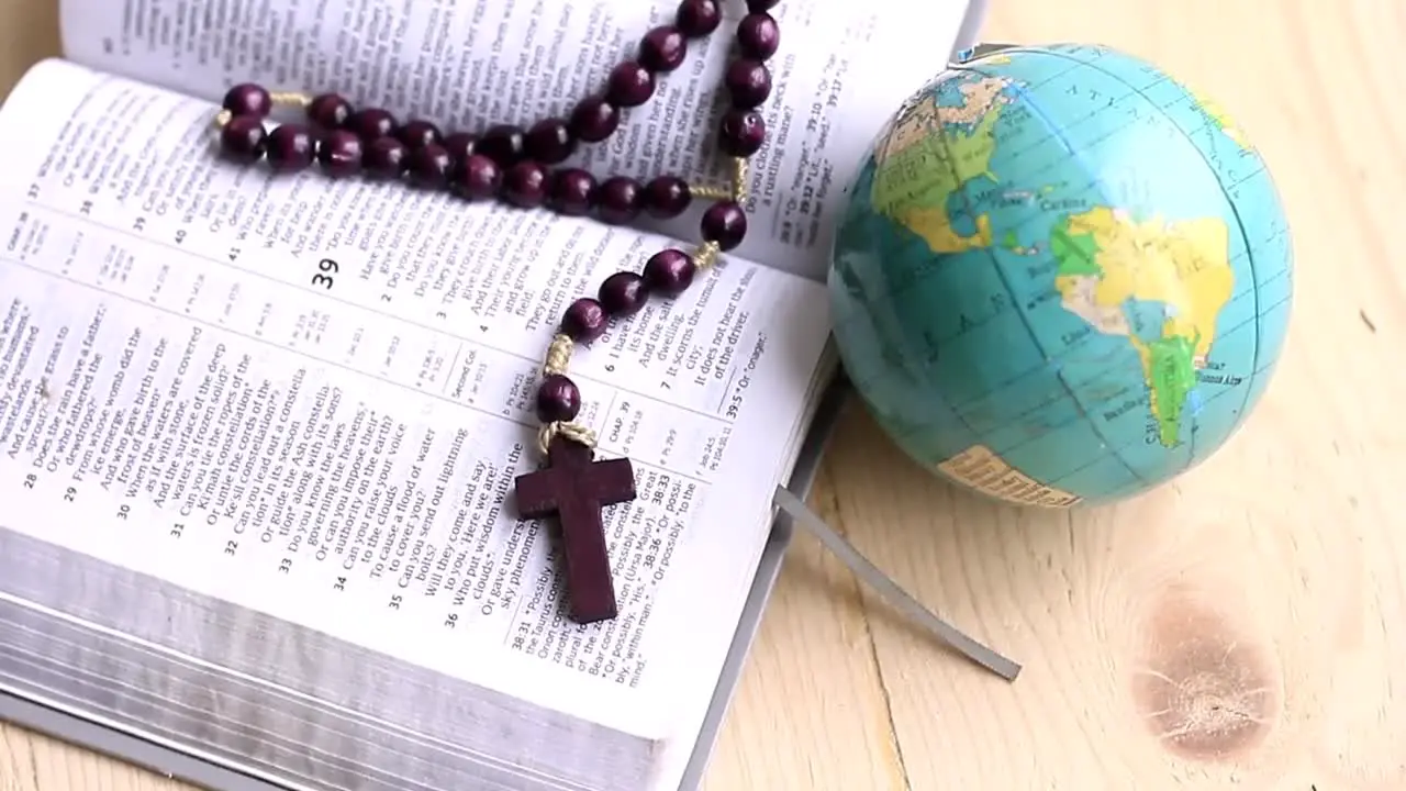 praying to God with cross on bible on table with globe no people stock video