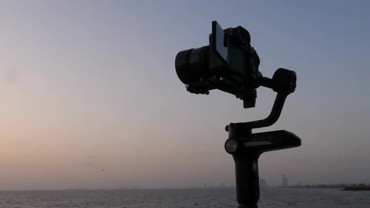 Silhouette Of Camera On Gimbal Stabiliser Filming Sunset Over Ocean