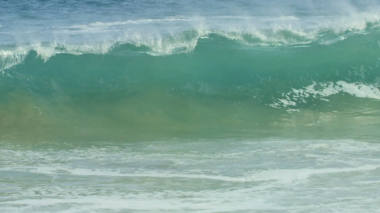 Blue Green Wave Cresting and Crashing into Shore in Slow Motion