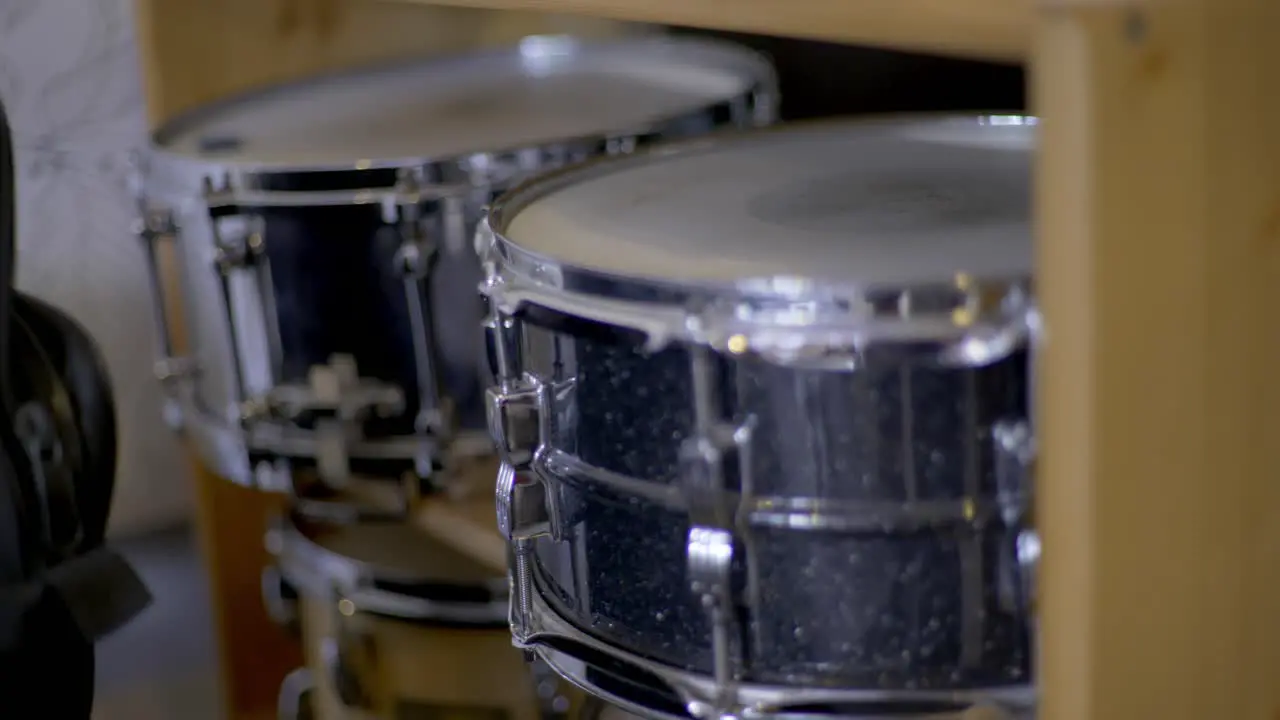 Two snare drums laying in a wooden shelf in a recording studio