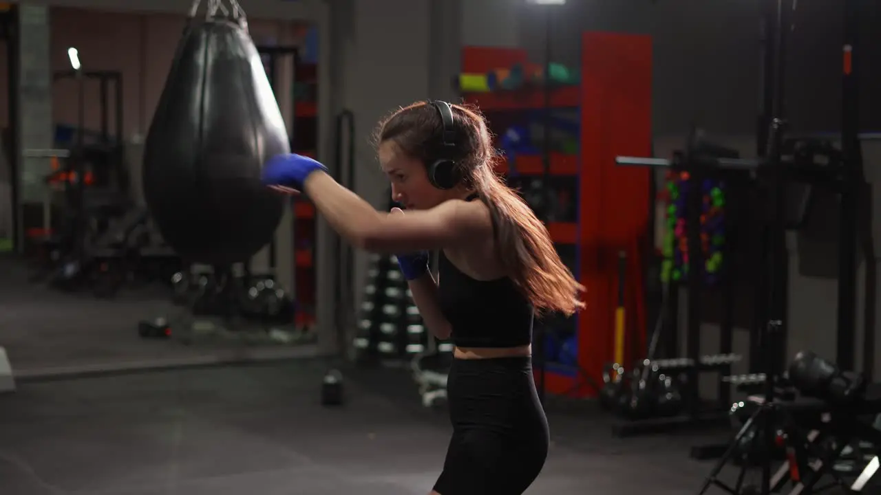 Female Boxer Performing Active Punching In Bandages Wearing Headphones