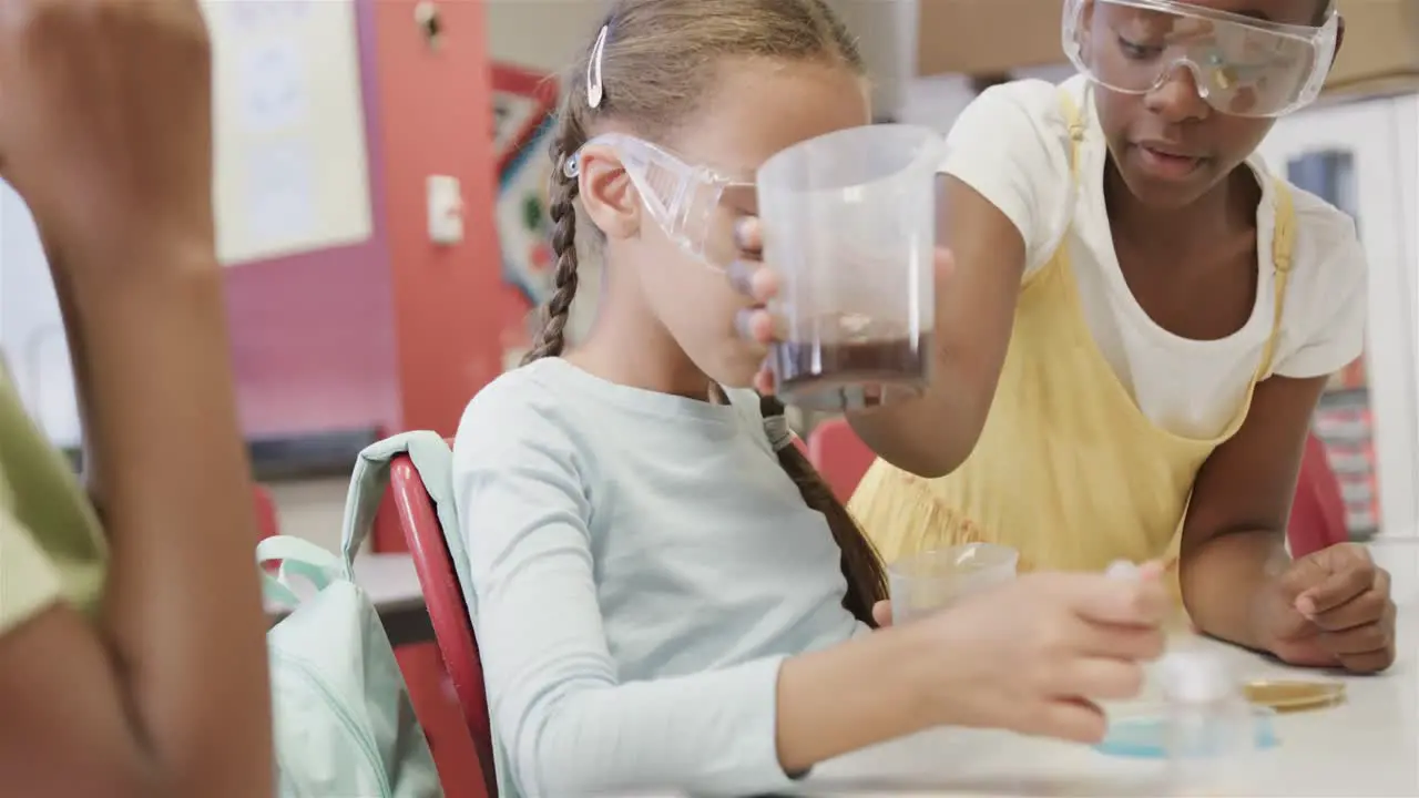 Happy diverse schoolgirls doing experiments in lab in slow motion at elementary school