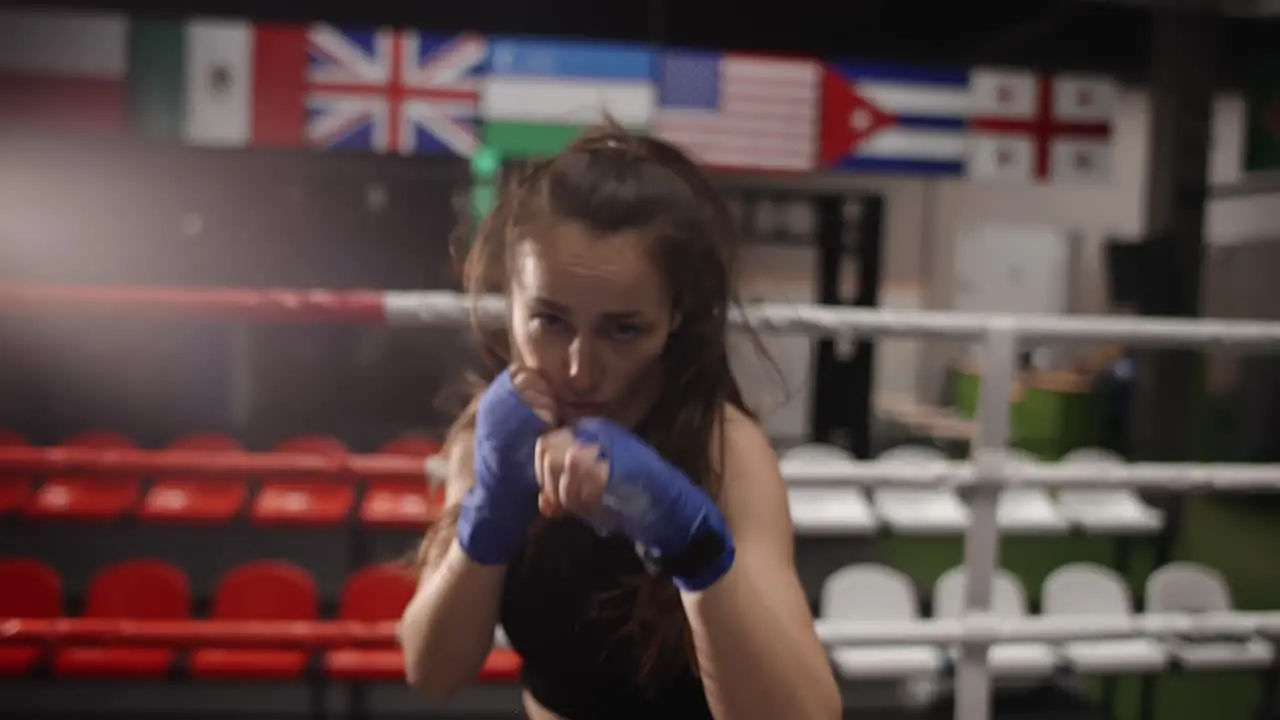 Active Female Boxer Punching Camera During Training In Bandages