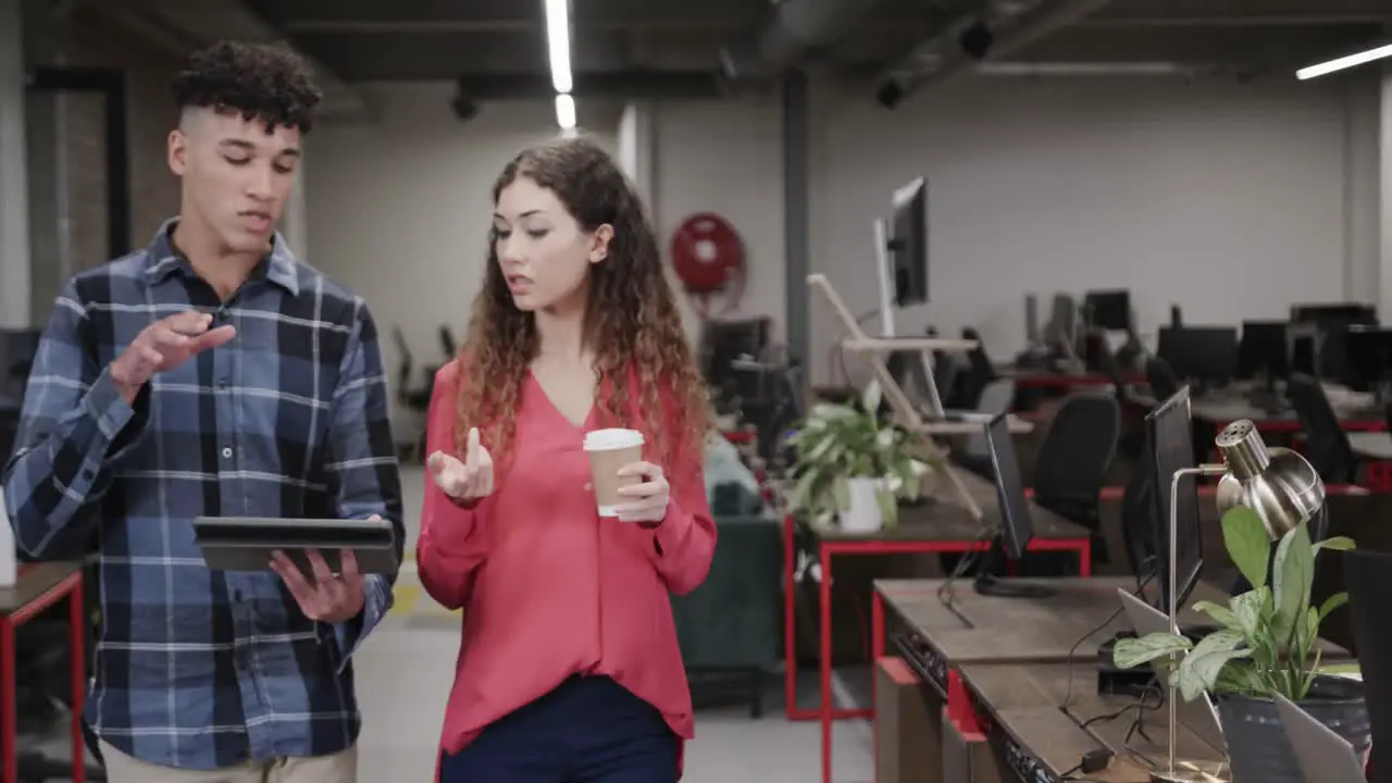 Two diverse creative designers in discussion at tablet in casual office slow motion