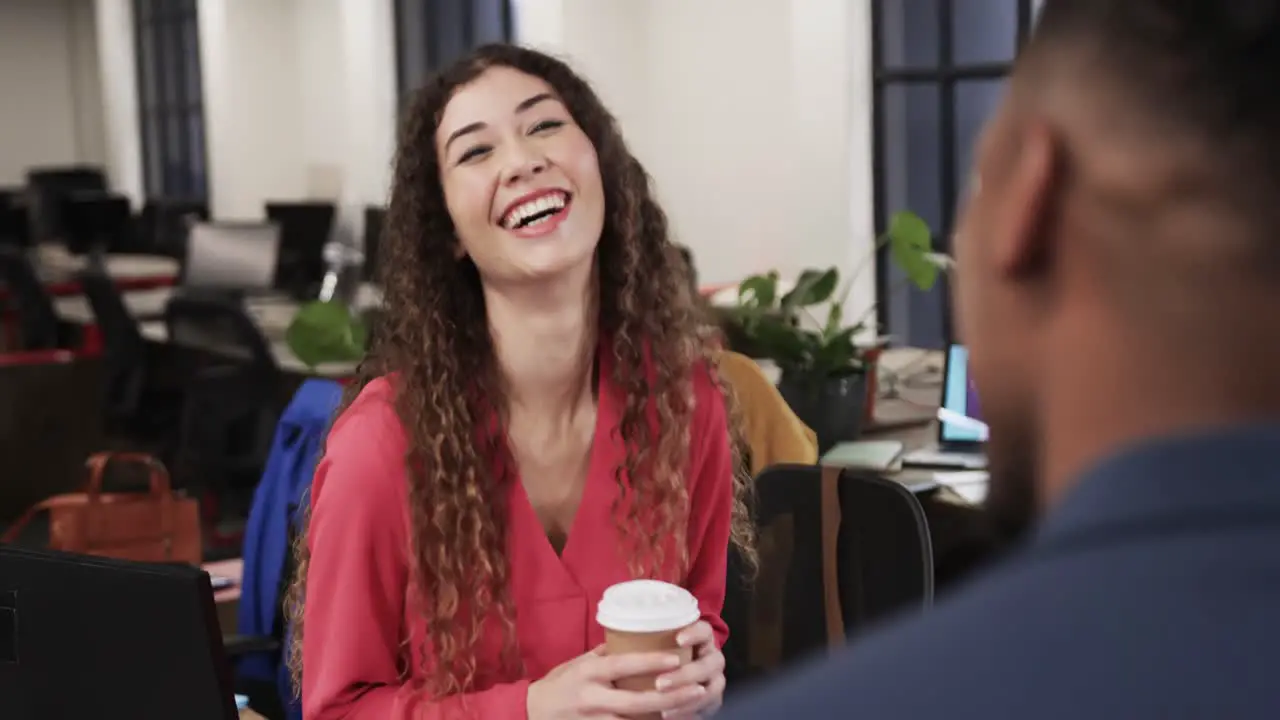 Two happy diverse creative colleagues in discussion in casual office slow motion