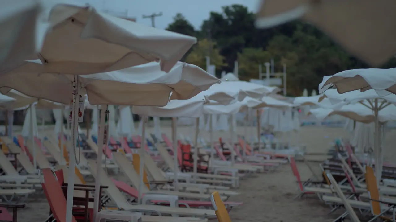 Empty sunbeds under umbrellas on resort in windy evening