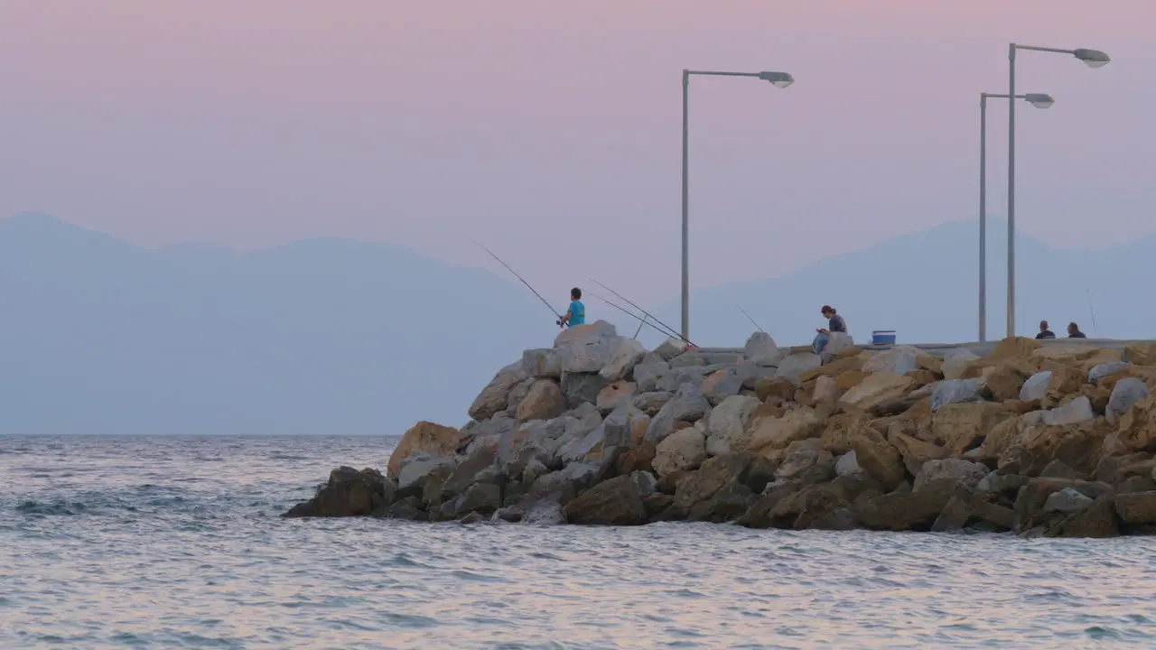 People fishing and relaxing on pier in the sea evening scene Greece