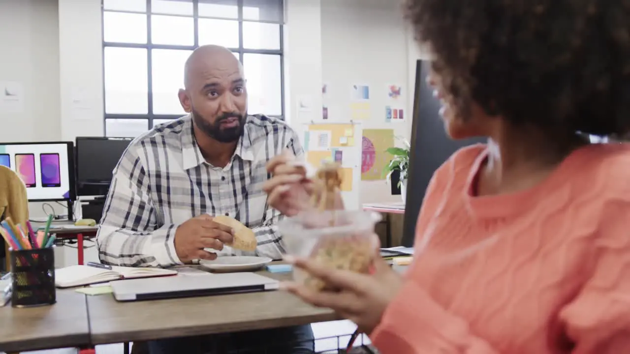 Two happy diverse creative colleagues in discussion during lunch in casual office slow motion