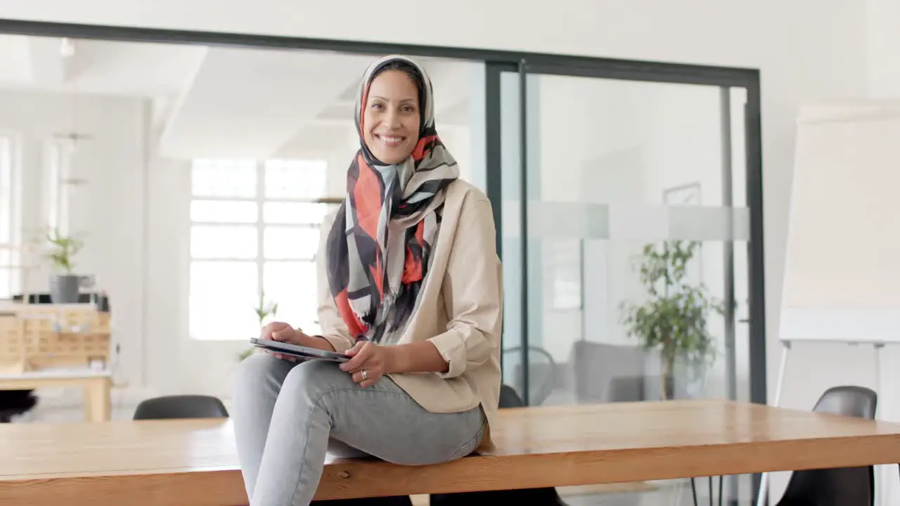 Portrait of happy biracial businesswoman with tablet in office in slow motion