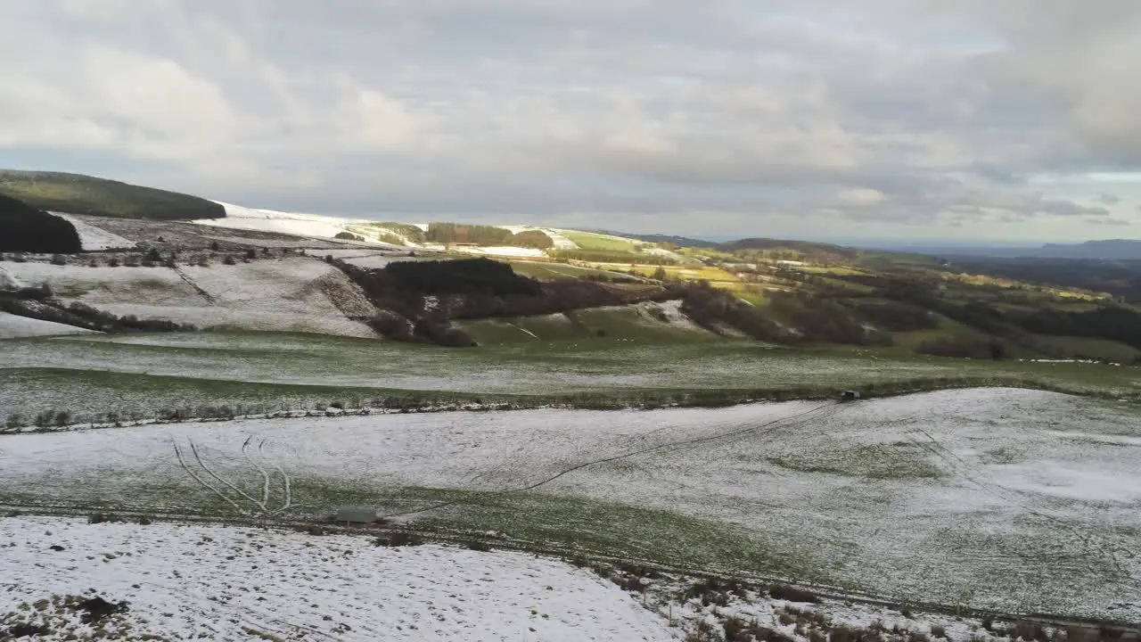 Snowy rural cold winter valley countryside aerial agricultural farmland landscape right descend