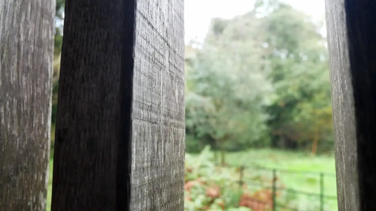 Raining weather in rural mountain countryside through rustic oak wood barn beams window fast left dolly