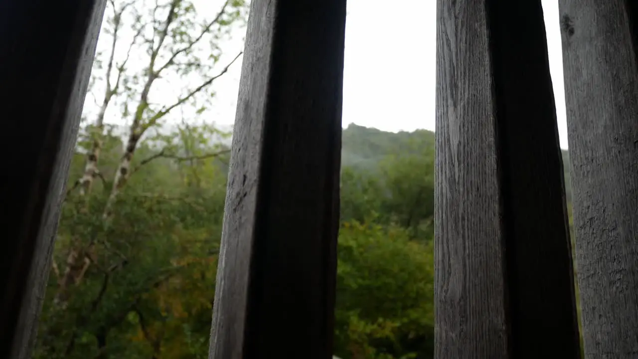 Raining weather in rural mountain countryside through rustic oak wood barn beams window dolly right looking up