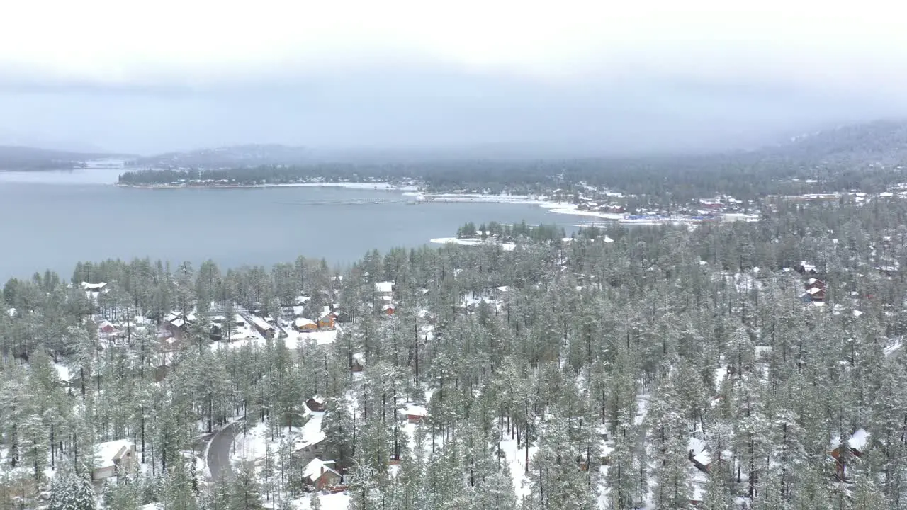 Aerial view panning over Big Bear Lake during a spring snow storm in the Southern California Mountains