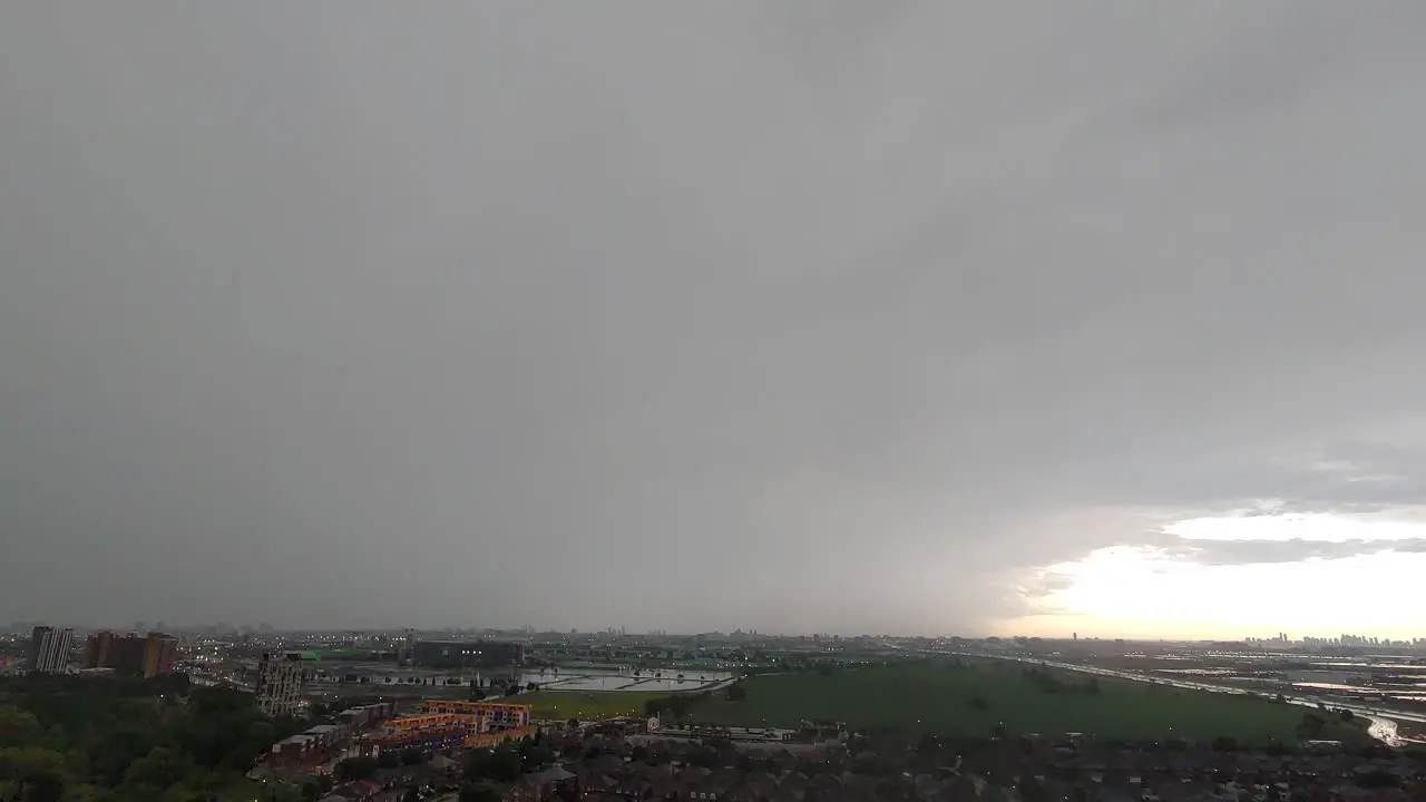 Rainy day timelapse cloudy sky lightining over the city view and green meadow