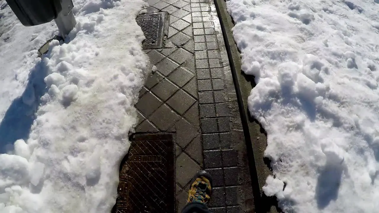 Man walking along a clear path on snowed streets