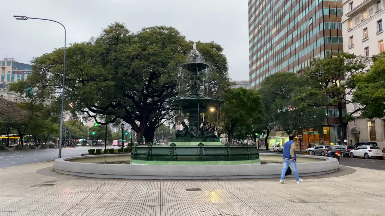 Fountain between two roads a man walks past the fountain