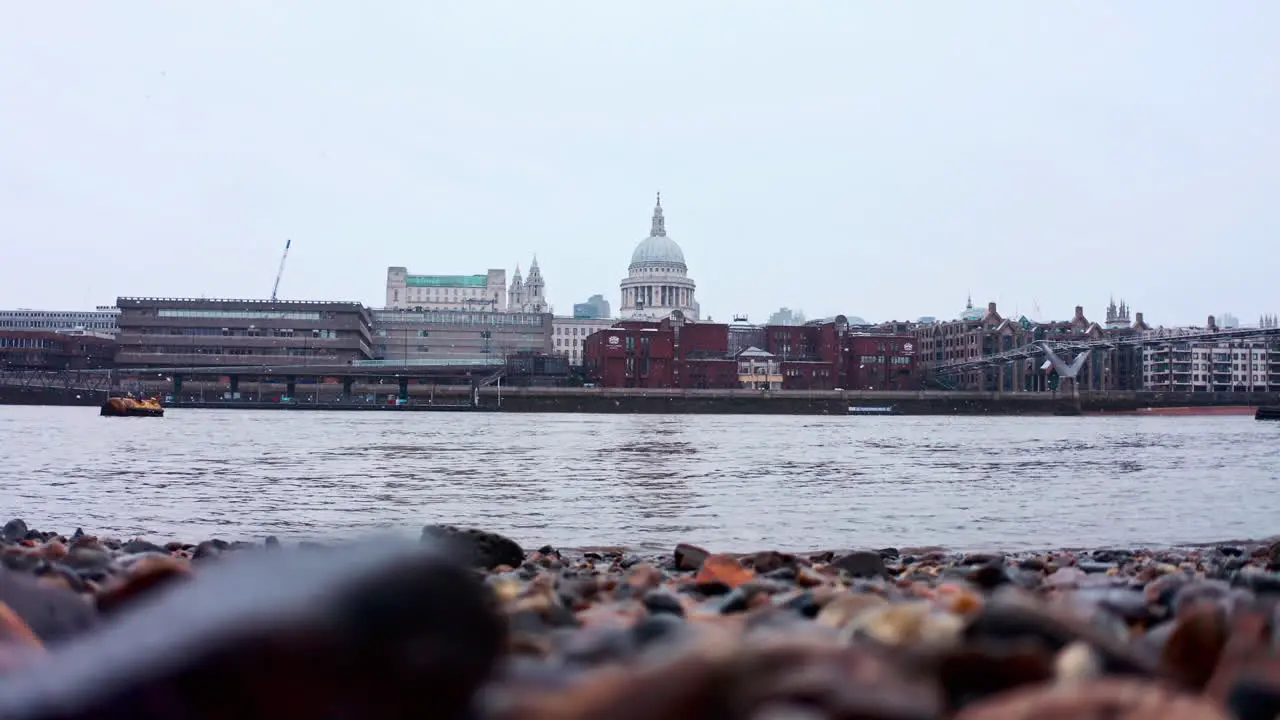 Low shot of snow falling from thames river bank towards st pauls cathedral London