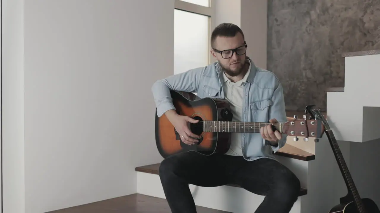 Male Musician Adjusting And Playing Guitar At Home