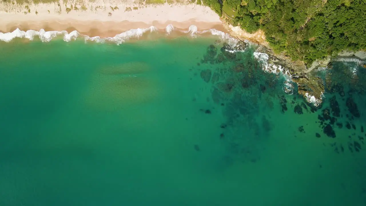 Calming aerial view of waves lapping up along the shoreline on a summers day