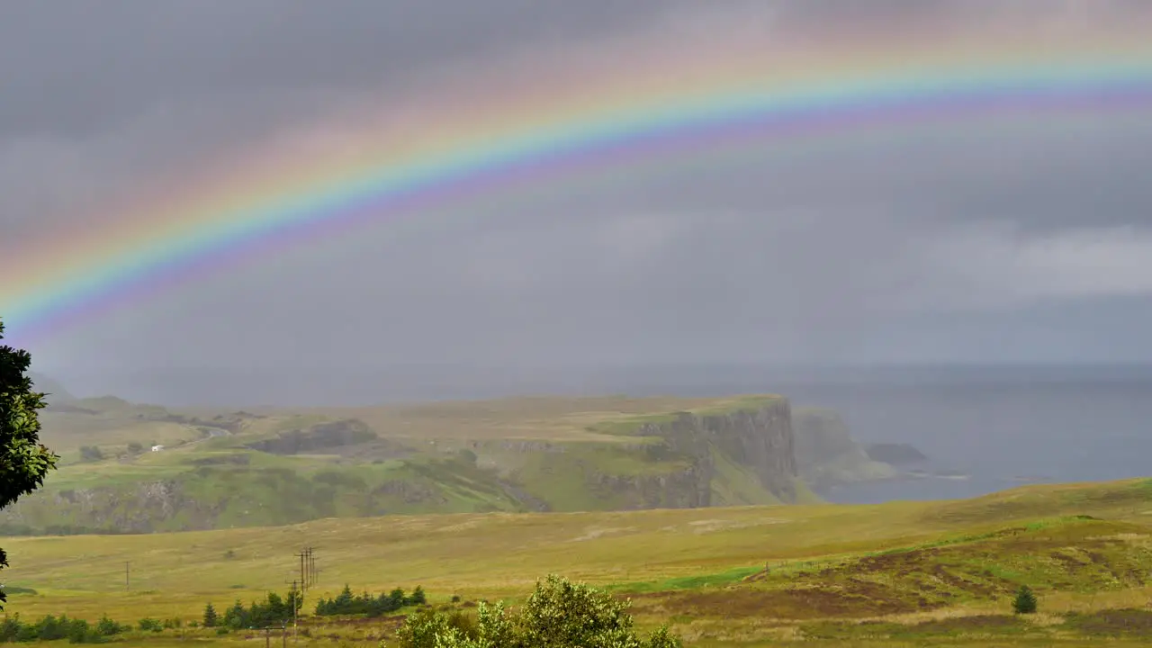 Rainbow above Meadows and Cliffs on the Isle of Skye in Scotland with Clouds