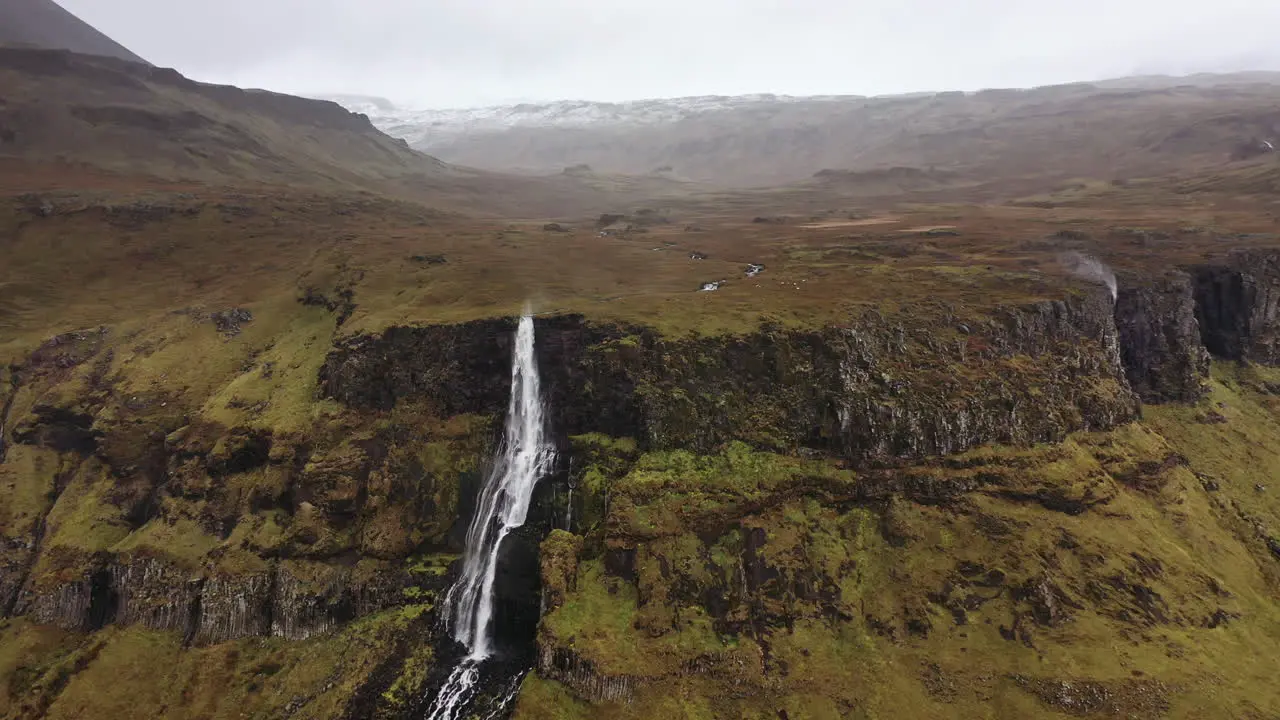 Drone flight towards waterfall on a windy winter day