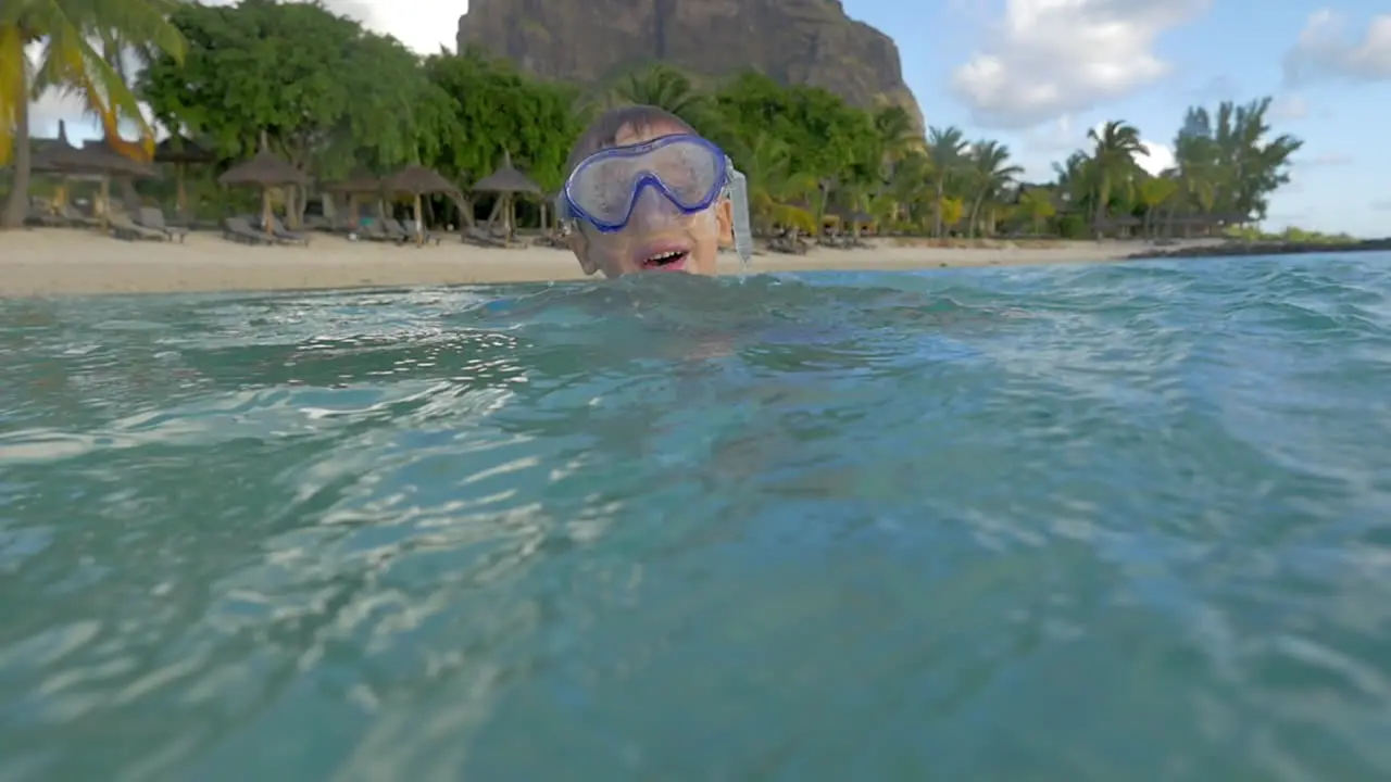 Slow motion view of small boy swimming in the Indian Ocean in the snorkeling mask and take a picture Port Louis Mauritius Island