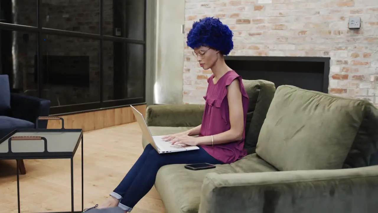 Biracial businesswoman with blue afro and using laptop in office slow motion