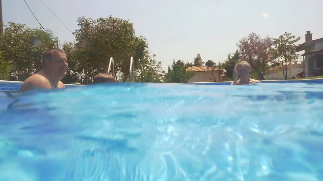 Boy learning swimming in the pool with his parents and granny